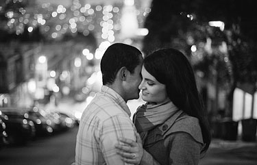 Balck and white images of the couple hugging with San Francisco street lights in the background